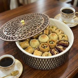 A luxury candy or gift box made from recycled wood and fine leather, decorated with Arabic calligraphy.